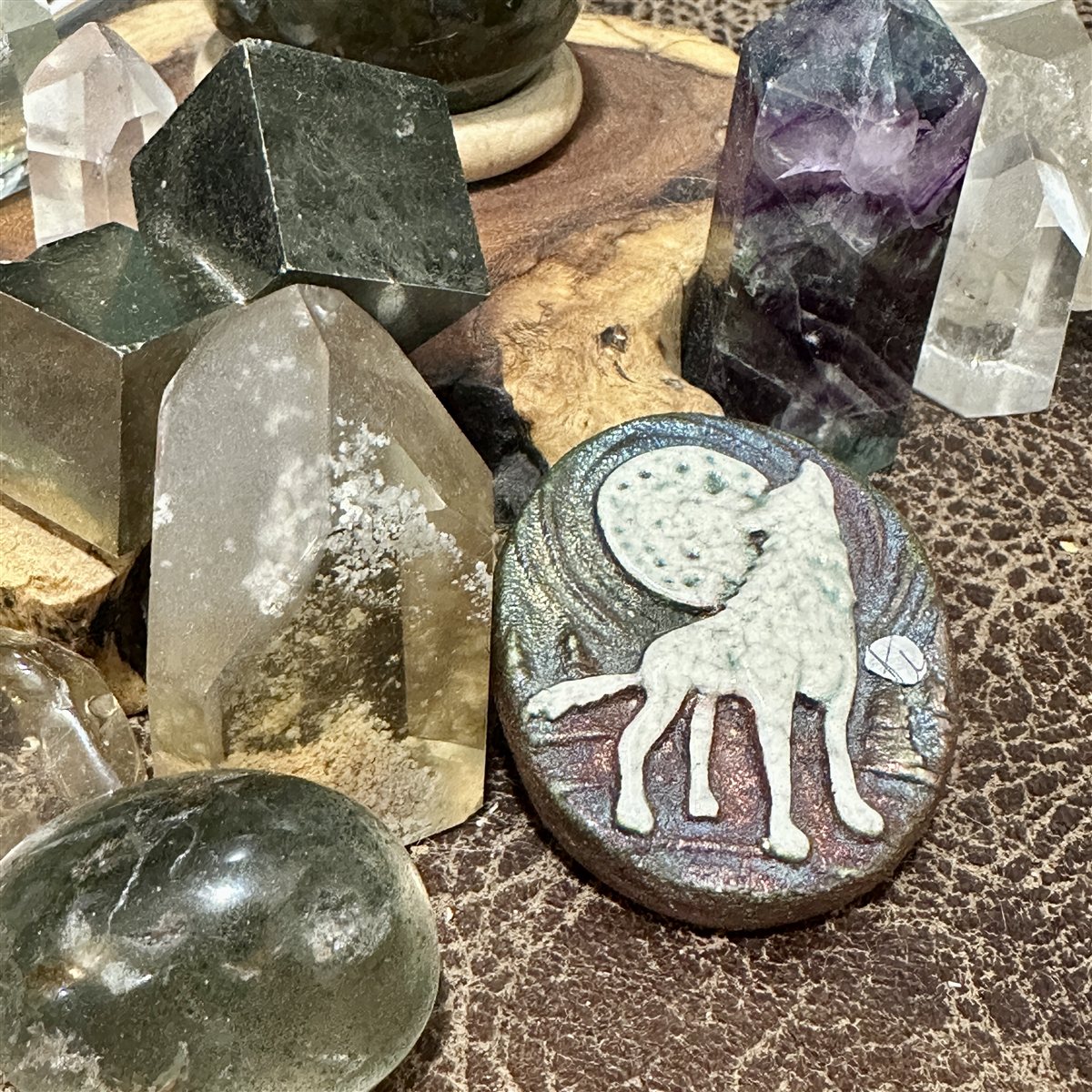 A carved stone of a wolf and moon, set among crystals.